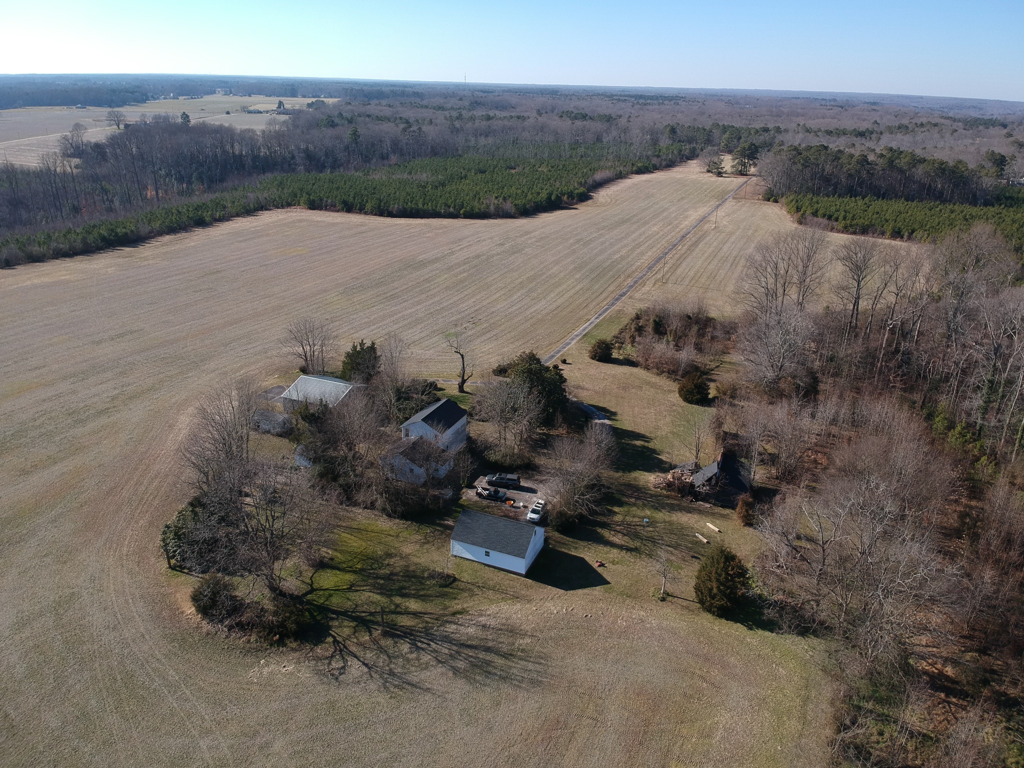Aerial view of open acreage, woodland, and a rural homestead
