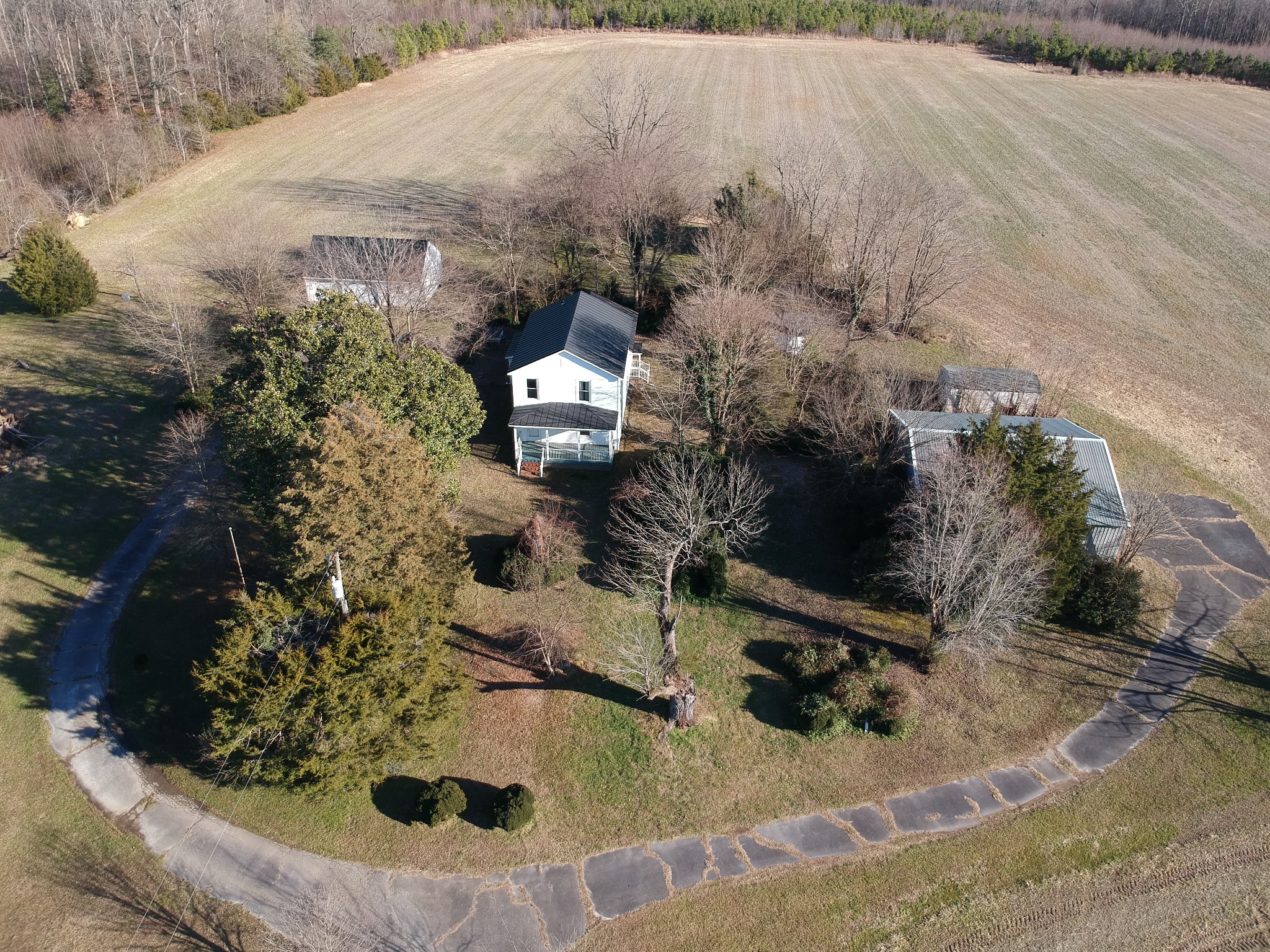 Aerial view of a white farmhouse, outbuildings, and surrounding fields